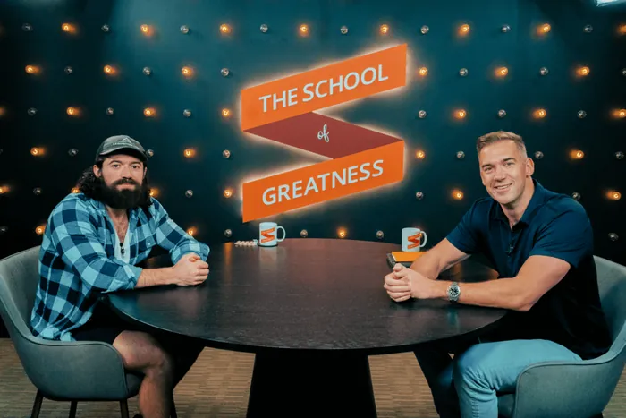 Alex Hormozi and Lewis Howes seated together in The School of Greatness studio